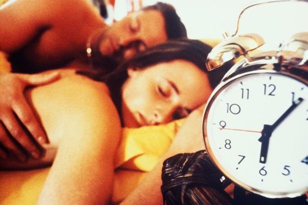 YOUNG COUPLE SLEEPING WITH ALARM CLOCK